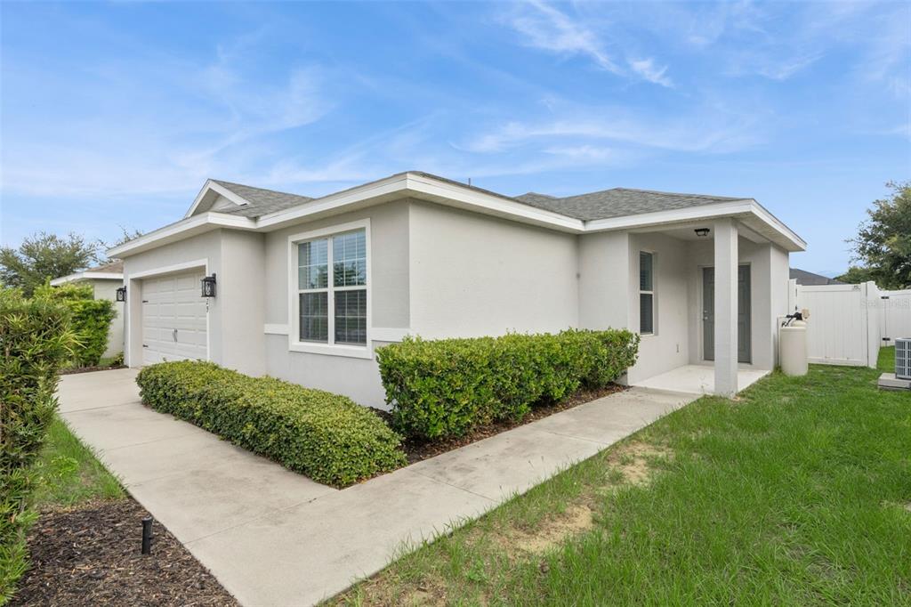 A single-story house with a light-colored stucco exterior, a garage, and a landscaped front yard — 229 SANDESTIN DR, HAINES CITY, FL