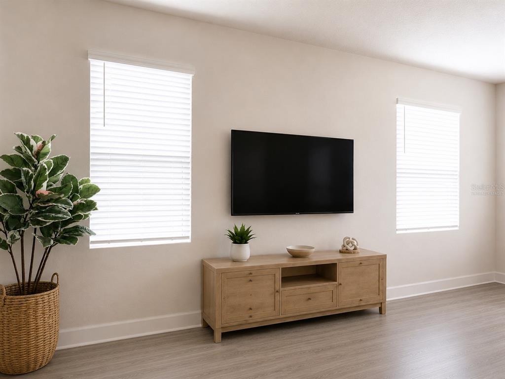 A living room features a wall-mounted television, a wooden media console, and a potted plant — 15084 CARAVAN AVENUE, ODESSA, FL
