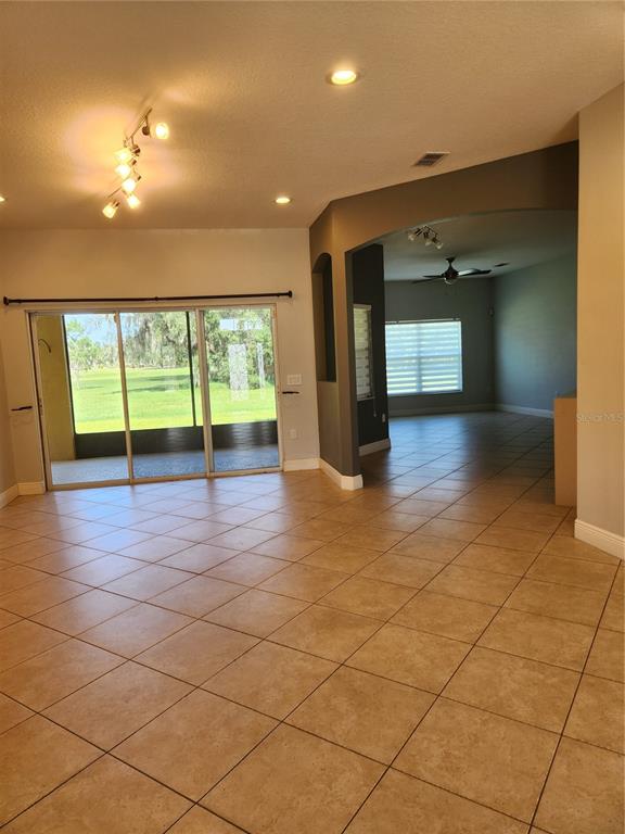 An open living area with tile floors, sliding glass doors, and an arched entryway — 3507 SUNSET ISLES BLVD., KISSIMMEE, FL
