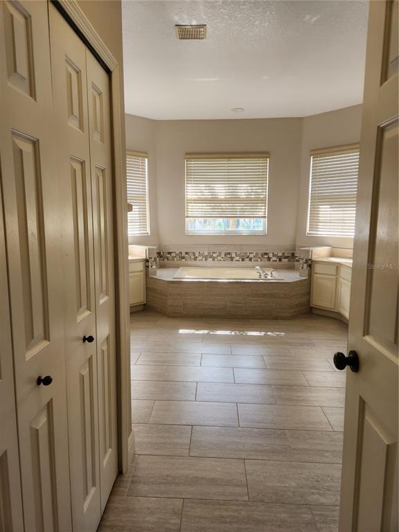 A bathroom features a central soaking tub, tile flooring, and dual vanities under three windows — 3507 SUNSET ISLES BLVD., KISSIMMEE, FL