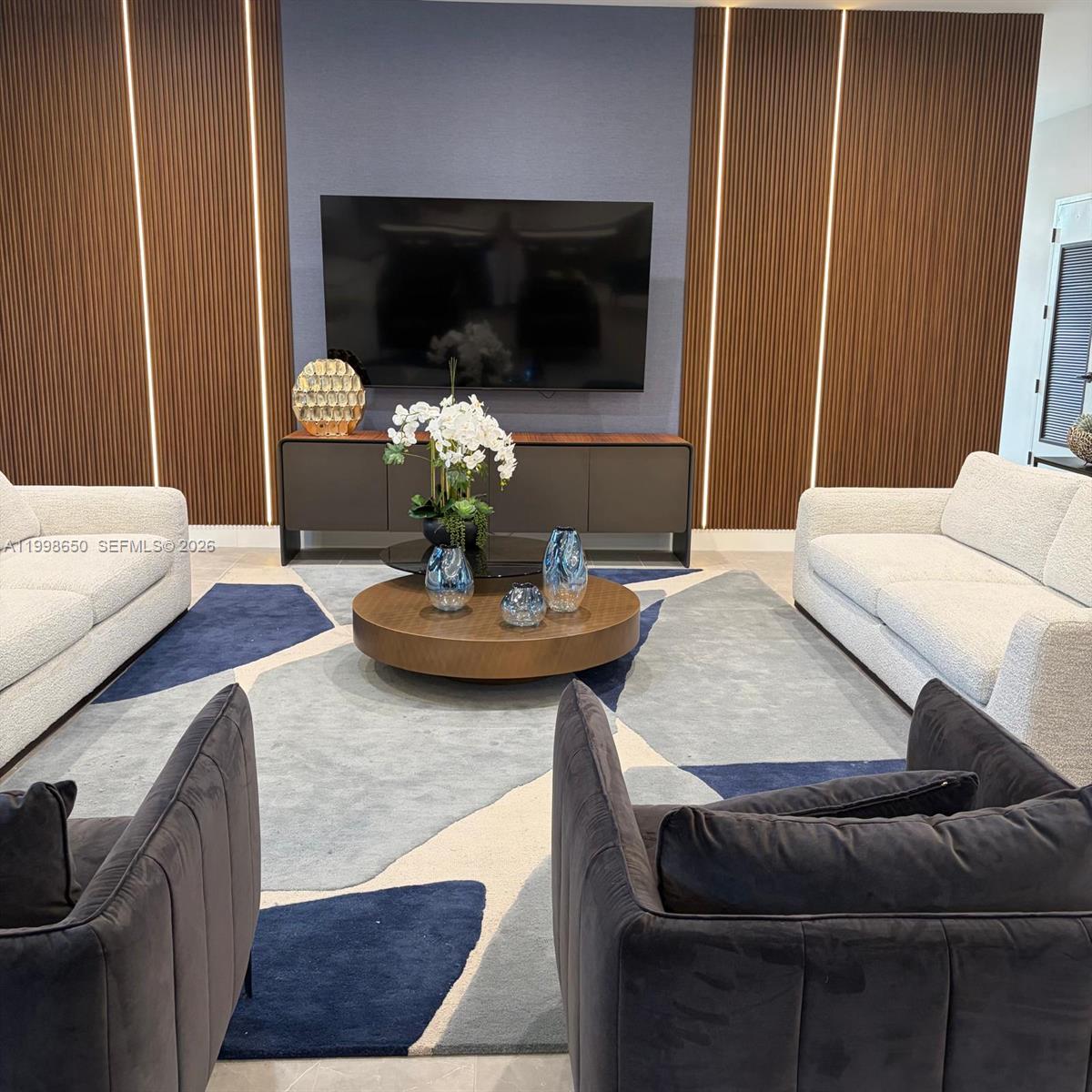 A living room features two white sofas, two dark armchairs, and a wood-paneled accent wall — 23320 SW 127th Ct, Homestead FL 33032, HOMESTEAD, FL