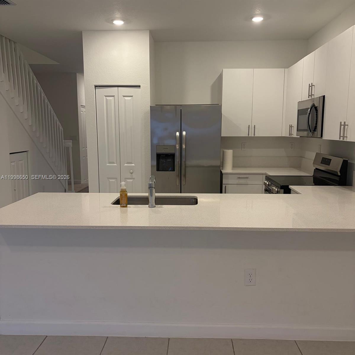 A kitchen features white cabinets, stainless steel appliances, and a white quartz breakfast bar — 23320 SW 127th Ct, Homestead FL 33032, HOMESTEAD, FL