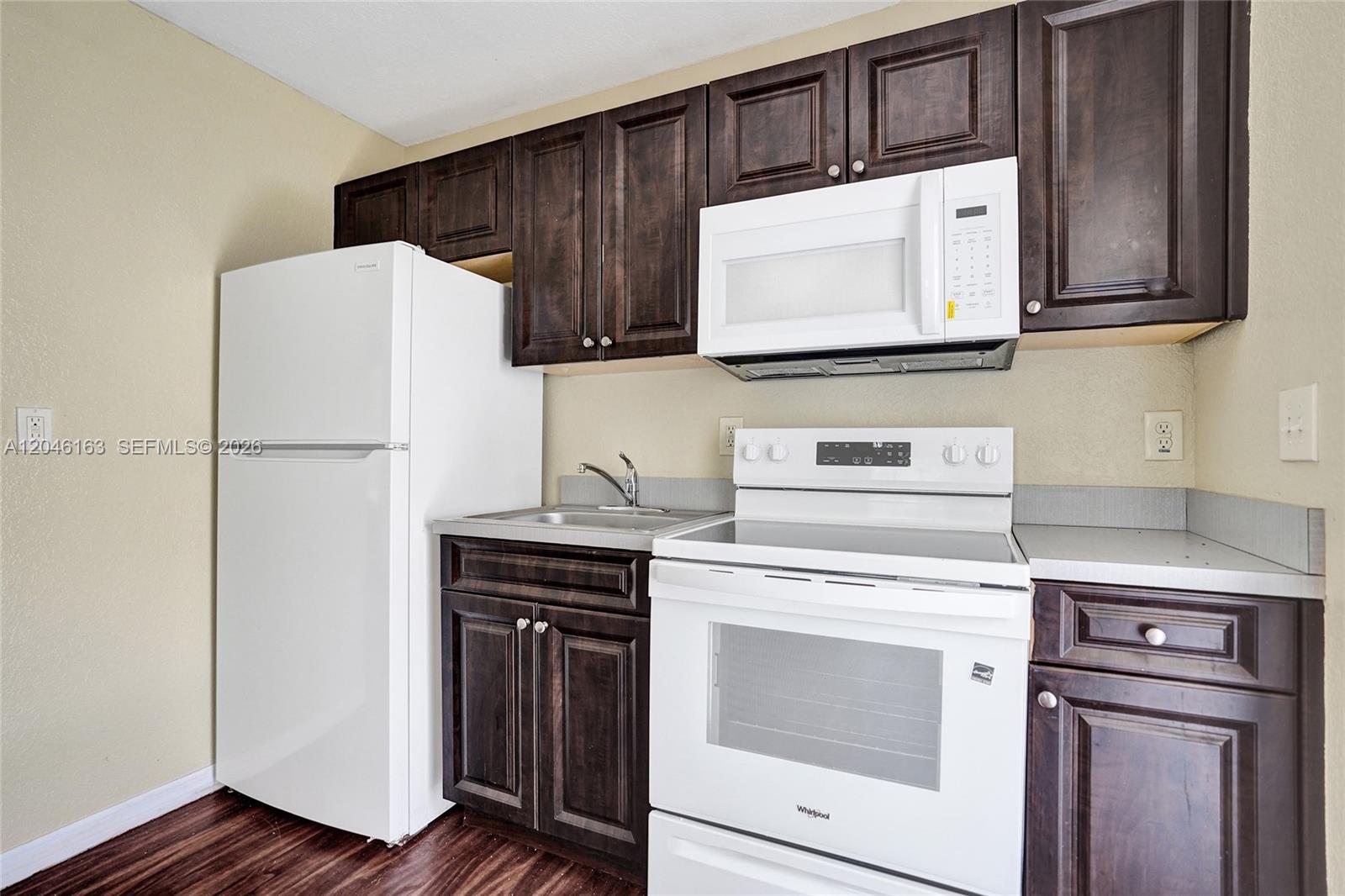 A kitchen features dark wood cabinets, white appliances, and a small stainless steel sink — 727 22nd St # A, West Palm Beach FL 33407, WEST PALM BEACH, FL