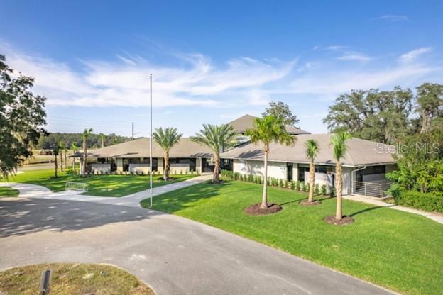 A low-slung building with a gray roof sits on a grassy lot with palm trees — 2201 NW 21ST STREET, OCALA, FL