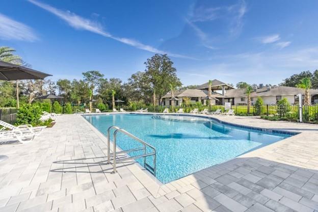 A rectangular swimming pool with a metal ladder sits on a paved patio near buildings — 2201 NW 21ST STREET, OCALA, FL