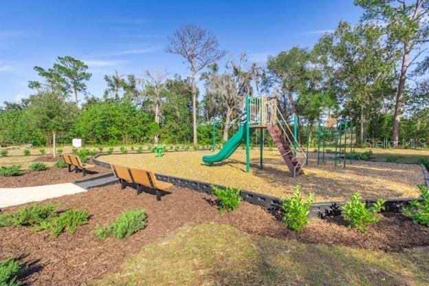 A playground with a green slide, climbing structure, and benches sits on wood mulch — 2201 NW 21ST STREET, OCALA, FL