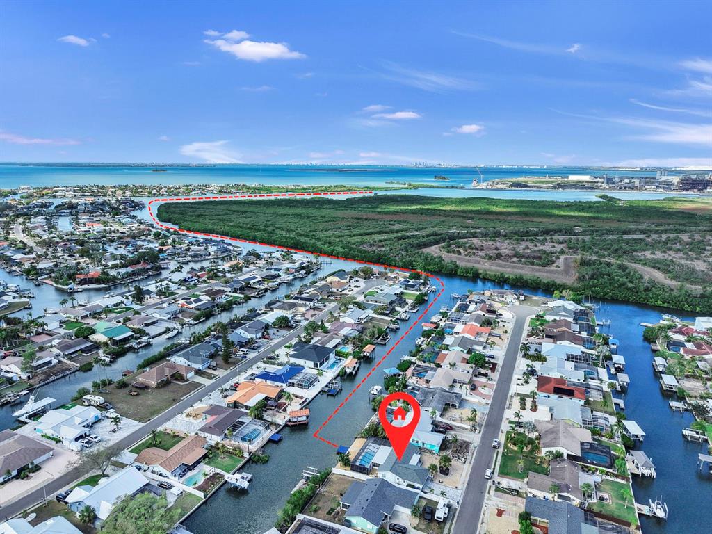 An aerial view shows a waterfront house with a pool along a canal near mangroves — 6512 SENEGAL PALM WAY, APOLLO BEACH, FL