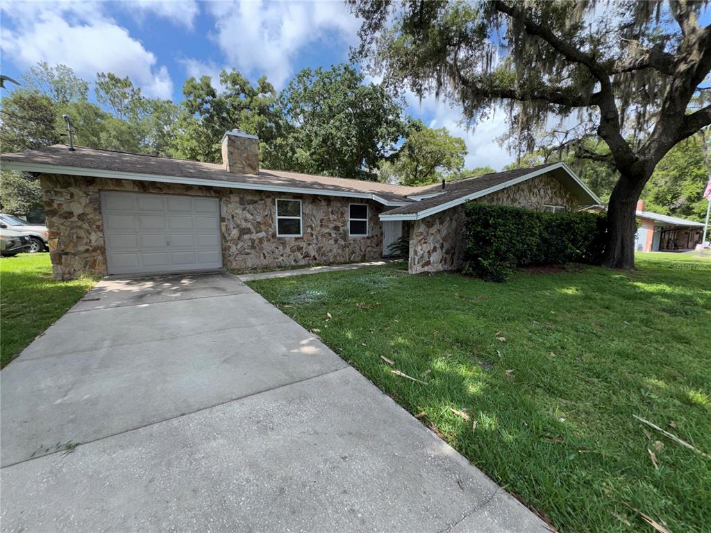 A single-story house with a stone facade, a one-car garage, and a concrete driveway — 3000 E BRYANT STREET, INVERNESS, FL