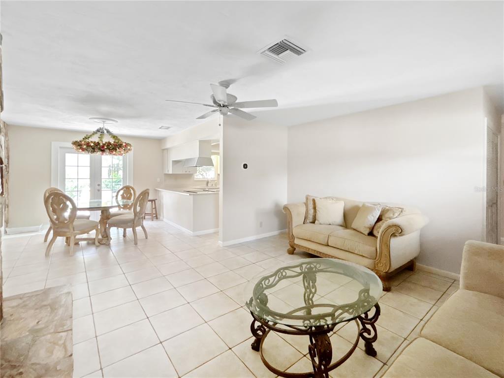 An open-concept living and dining area features tile flooring, a glass coffee table, and furniture — 3000 E BRYANT STREET, INVERNESS, FL