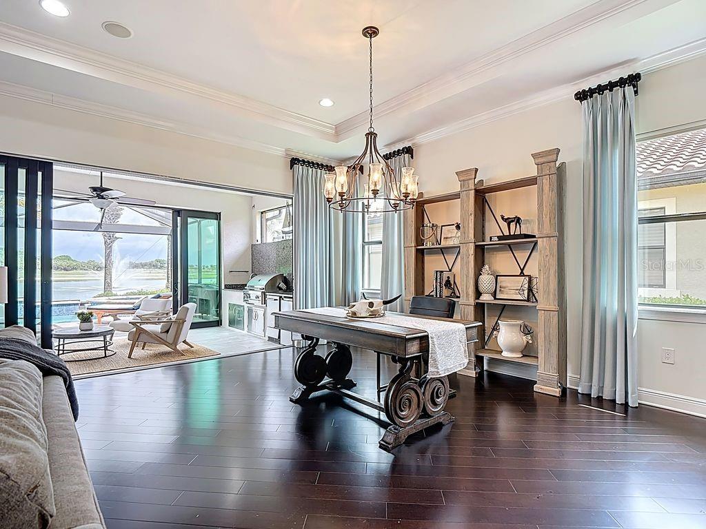 A home office features a wooden desk, open shelving, dark hardwood floors, and sliding glass doors — 10264 PORTO ROMANO DRIVE, MIROMAR LAKES, FL