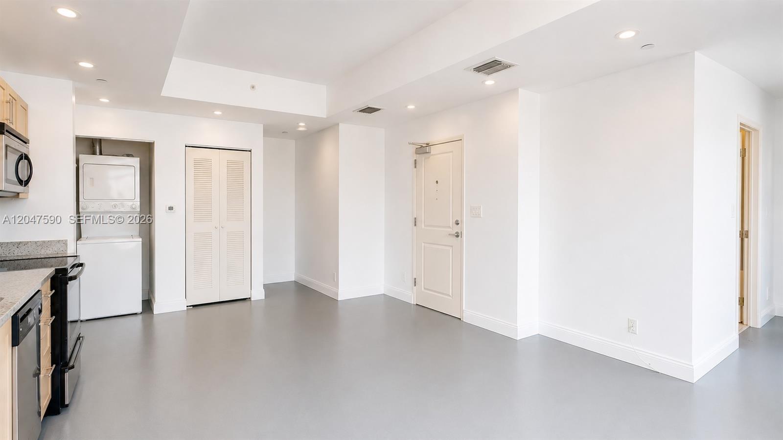 This room features white walls, gray flooring, a kitchen area, and a laundry closet — 111 E Flagler St # 810, Miami FL 33131, MIAMI, FL