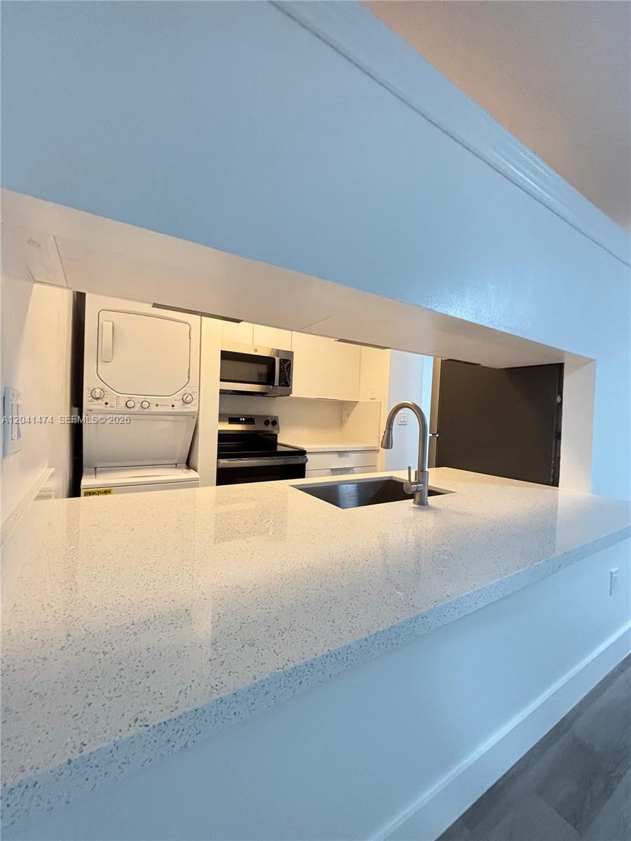 A kitchen features white countertops, a stainless steel sink, and a stacked washer-dryer unit — 15655 SW 74th Cir Dr # 6, Miami FL 33193, MIAMI, FL