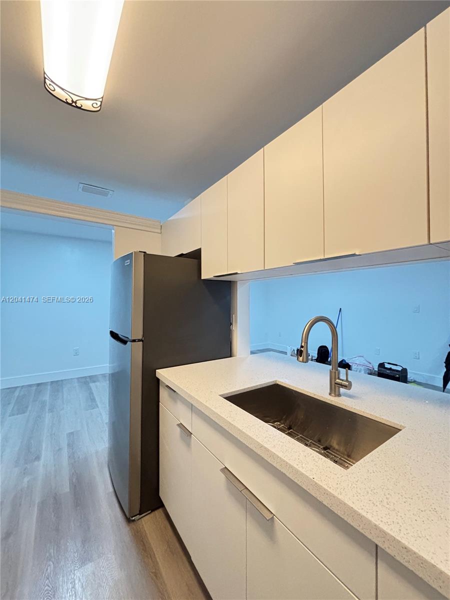 A kitchen features white cabinets, a stainless steel sink, and a dark refrigerator — 15655 SW 74th Cir Dr # 6, Miami FL 33193, MIAMI, FL