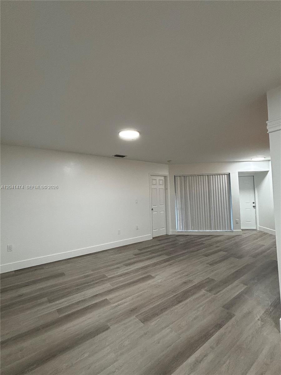 This empty room features white walls, a light fixture, and wood-look flooring — 15655 SW 74th Cir Dr # 6, Miami FL 33193, MIAMI, FL