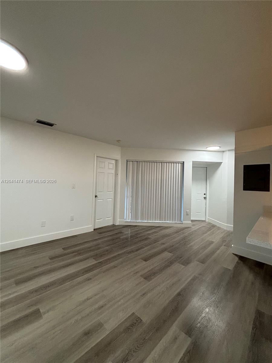An empty room features white walls, a window with vertical blinds, and wood-look flooring — 15655 SW 74th Cir Dr # 6, Miami FL 33193, MIAMI, FL