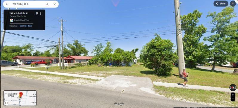 A street-level view shows a grassy lot with a small house and a person walking — 242 N HIGHWAY 22 A, PANAMA CITY, FL
