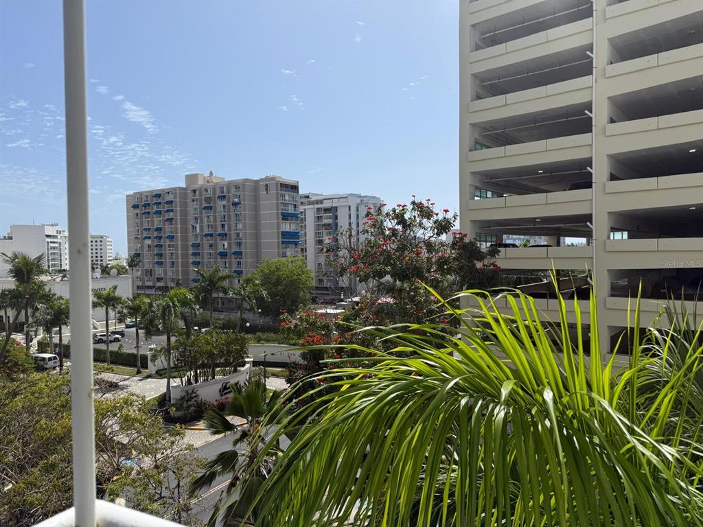 An outdoor view from a balcony shows palm trees, nearby buildings, and a parking garage — 6400 ISLA VERDE AVENUE UNIT 5D, CAROLINA, PR