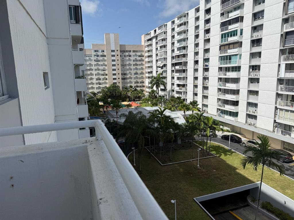 A view from a balcony overlooking a courtyard with palm trees and apartment buildings — 6400 ISLA VERDE AVENUE UNIT 5D, CAROLINA, PR