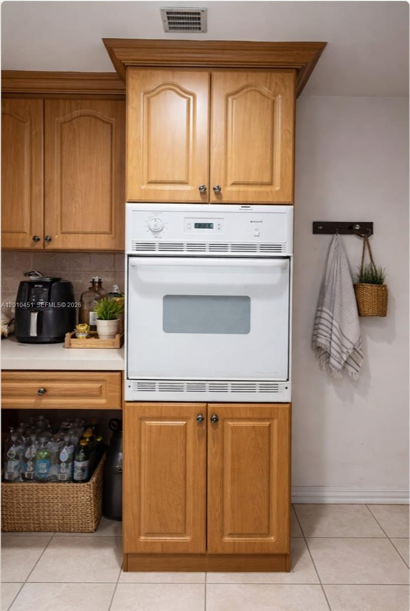 A kitchen features oak cabinets, a white wall oven, and a wicker basket for storage — 999 Brickell Bay Dr # 805, Miami FL 33131, MIAMI, FL