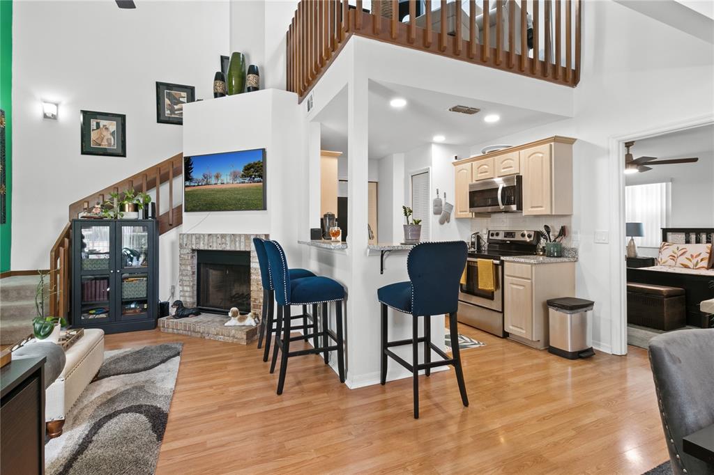 A living room with a brick fireplace, stairs, and a kitchen with a breakfast bar — 962 NEWCASTLE CIRCLE UNIT 206, LAKE MARY, FL