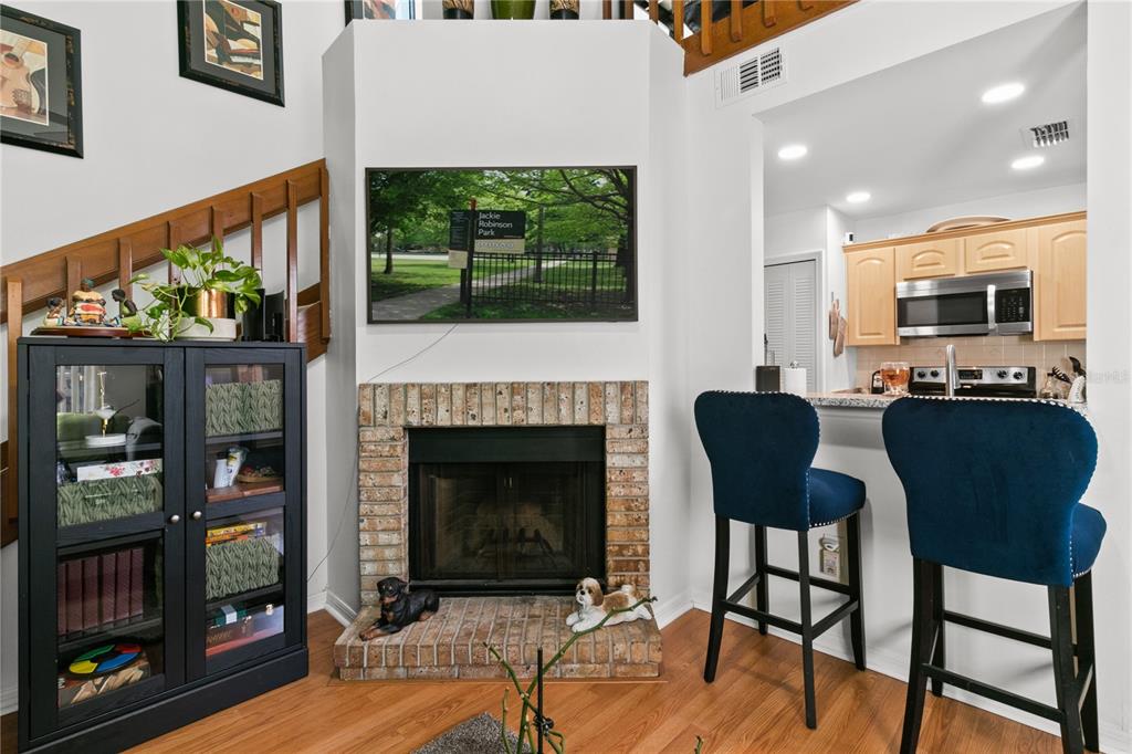 A living room features a brick fireplace, a wall-mounted television, and a breakfast bar — 962 NEWCASTLE CIRCLE UNIT 206, LAKE MARY, FL