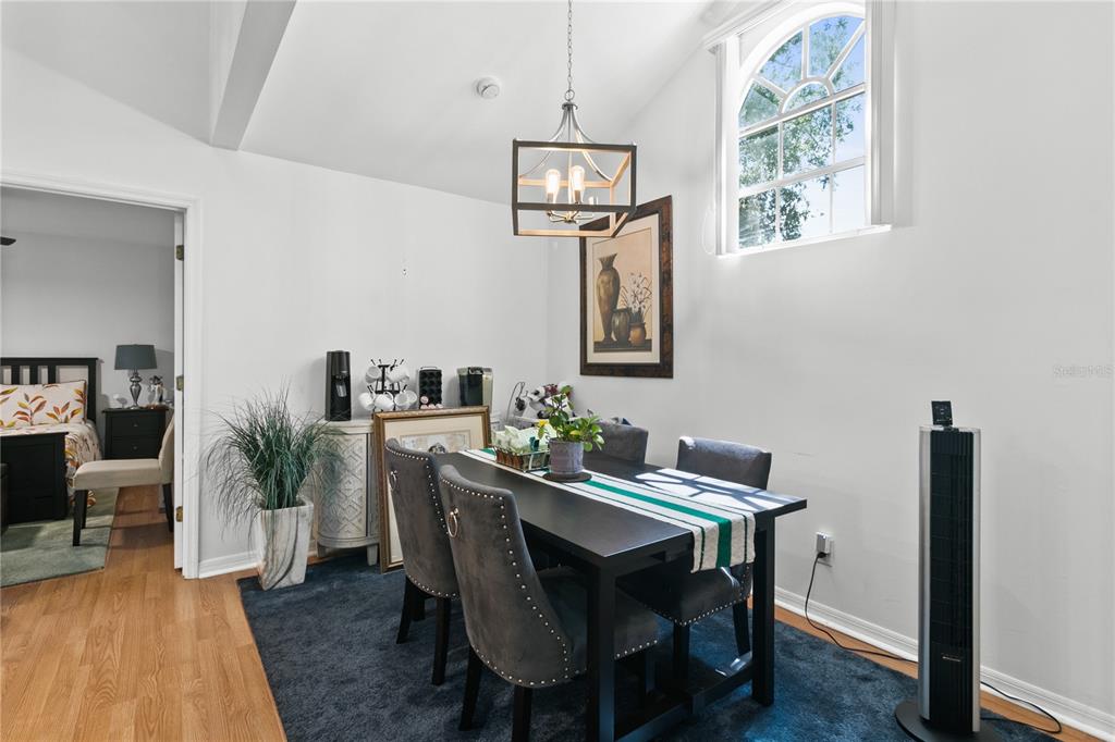 A dining room features a dark table, upholstered chairs, a pendant light, and a large window — 962 NEWCASTLE CIRCLE UNIT 206, LAKE MARY, FL