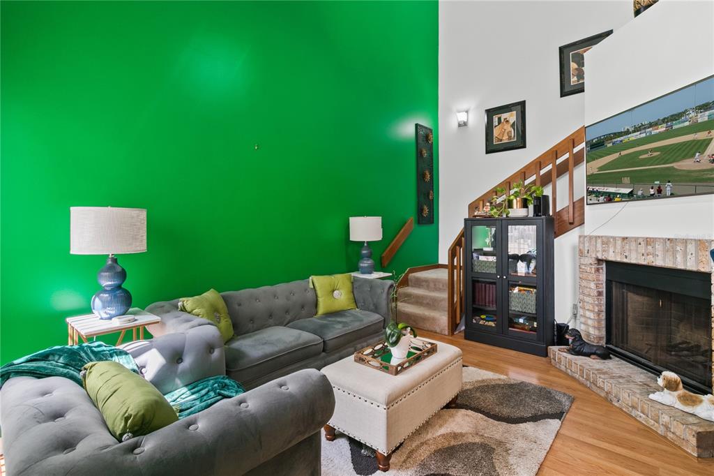 A living room features a bright green accent wall, gray sofa, fireplace, and wooden stairs — 962 NEWCASTLE CIRCLE UNIT 206, LAKE MARY, FL