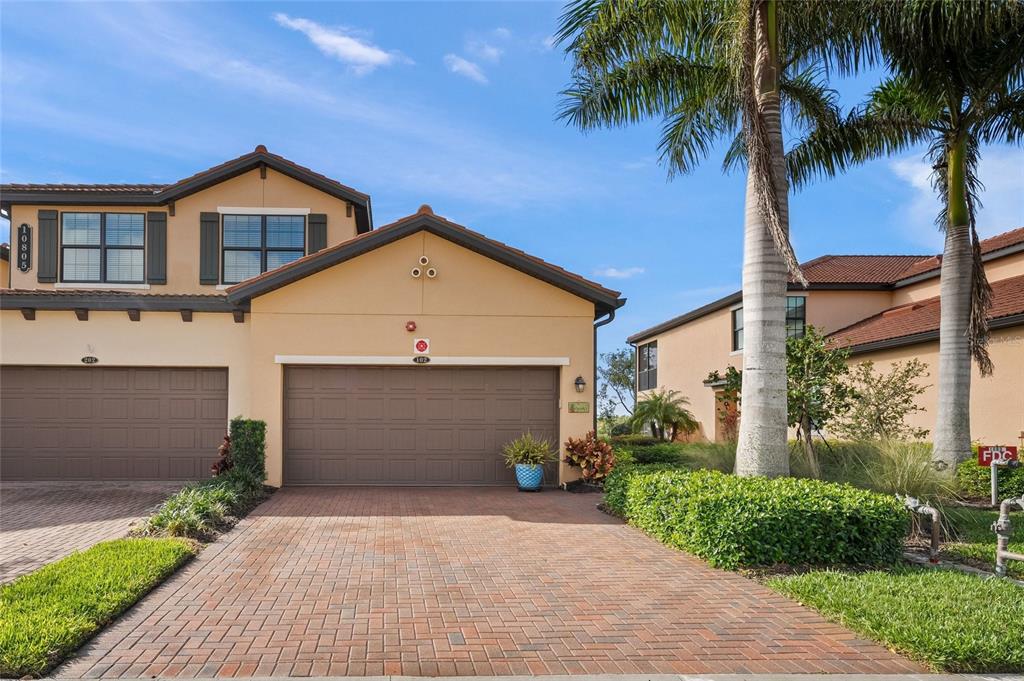 A tan two-story townhouse with a brick driveway and a two-car garage — 10805 TARFLOWER DRIVE UNIT 102, VENICE, FL