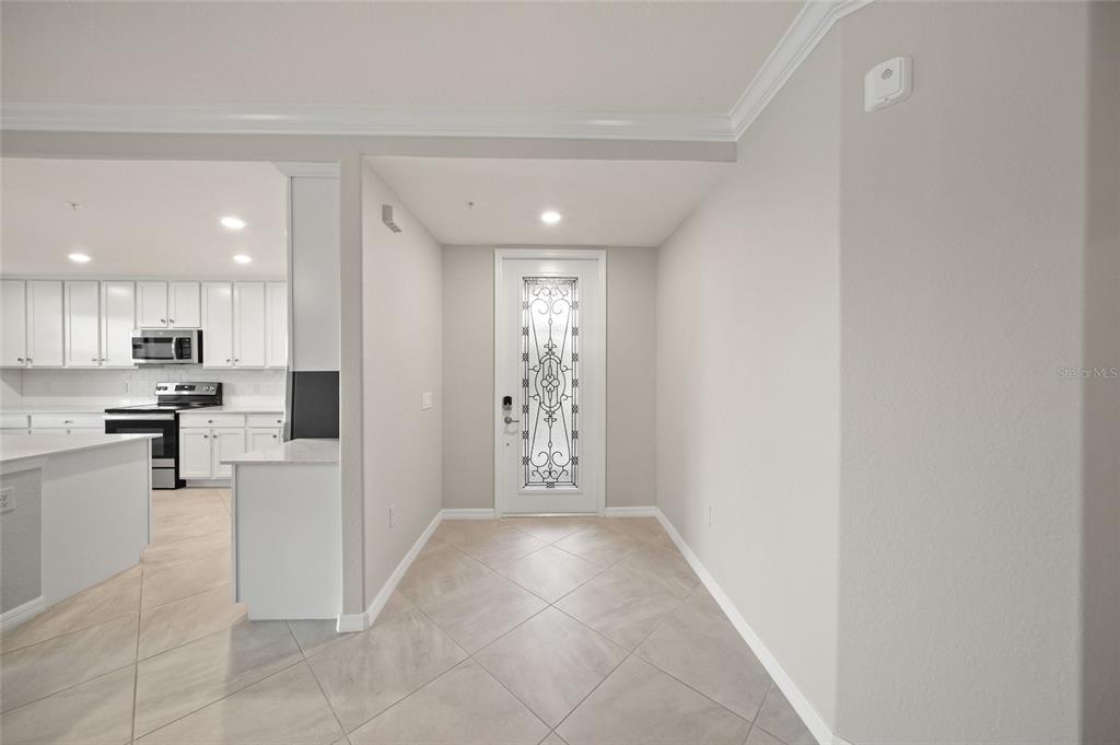 An entryway with tile flooring leads to a white front door with decorative glass — 10805 TARFLOWER DRIVE UNIT 102, VENICE, FL