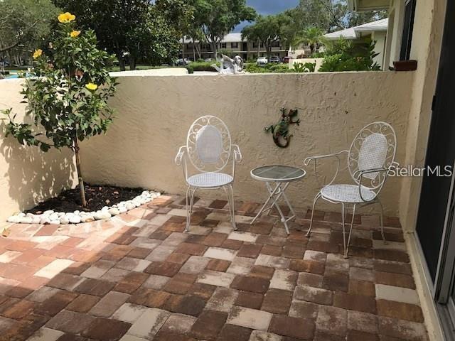 A small patio features two white metal chairs, a matching table, and a potted tree — 6892 W COUNTRY CLUB LANE, SARASOTA, FL