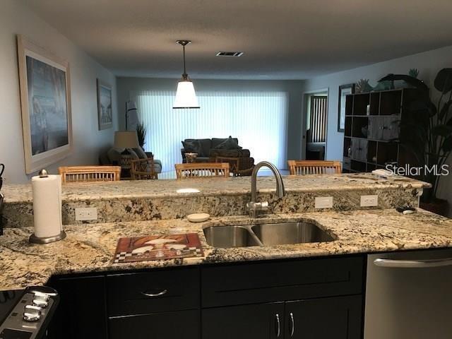 A kitchen with granite countertops and dark cabinets overlooks a living area with vertical blinds — 6892 W COUNTRY CLUB LANE, SARASOTA, FL