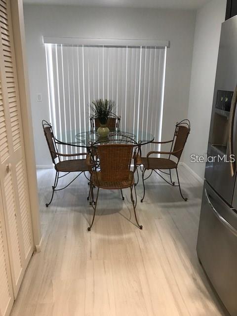 A dining area features a glass-topped table with four wicker chairs on light wood flooring — 6892 W COUNTRY CLUB LANE, SARASOTA, FL