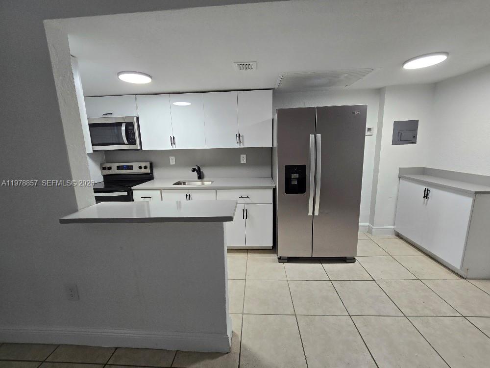 A kitchen features white cabinets, stainless steel appliances, a breakfast bar, and tiled flooring — 3901 SW 112th Ave # 38, Miami FL 33165, MIAMI, FL