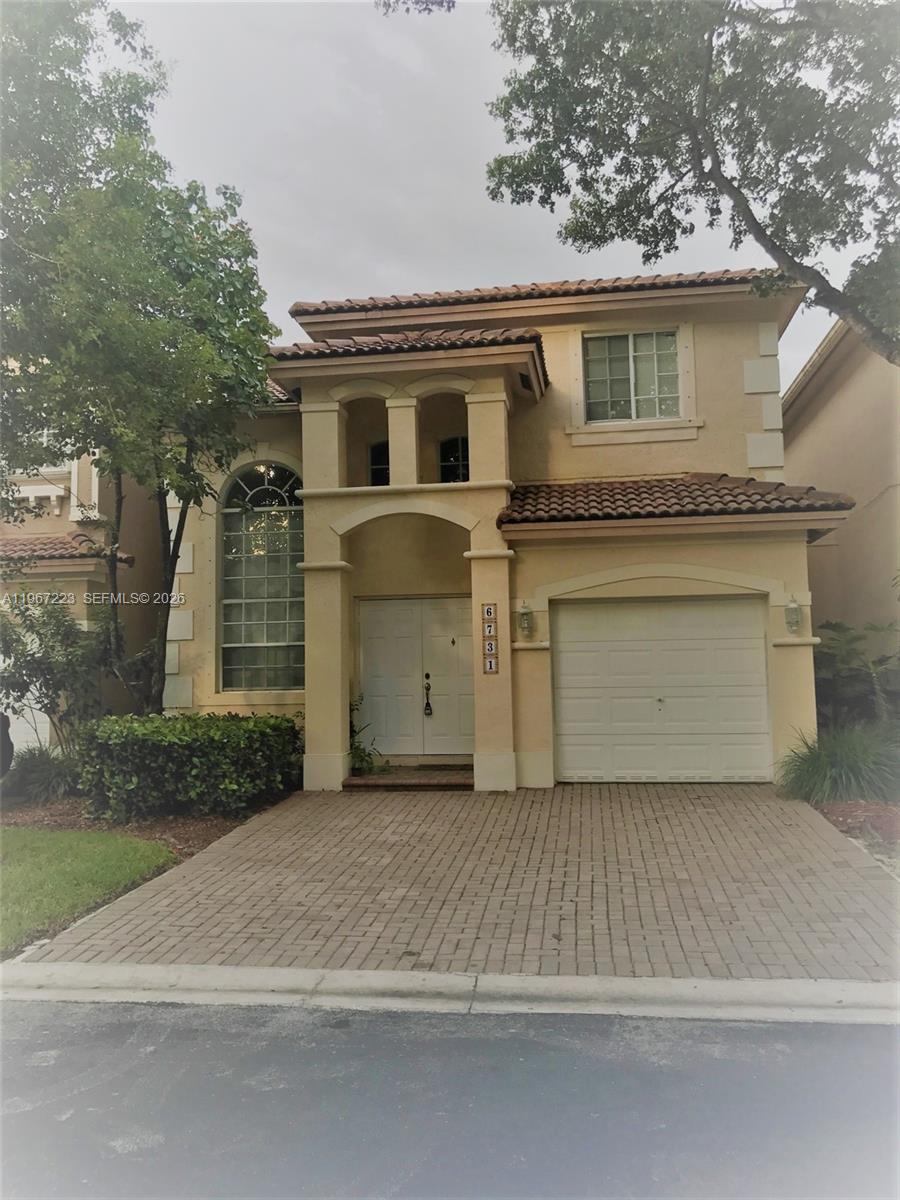 A two-story stucco house with a tiled roof, arched window, and a brick paver driveway — 6731 NW 107th Ct # 6731, Doral FL 33178, DORAL, FL