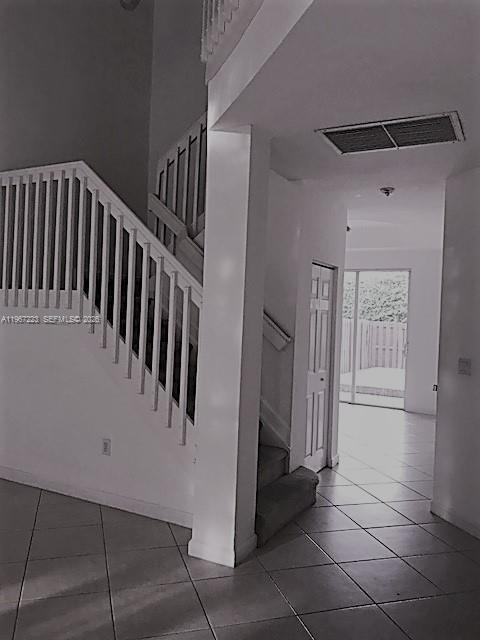 An interior view shows a staircase with white railings next to a tiled entryway — 6731 NW 107th Ct # 6731, Doral FL 33178, DORAL, FL