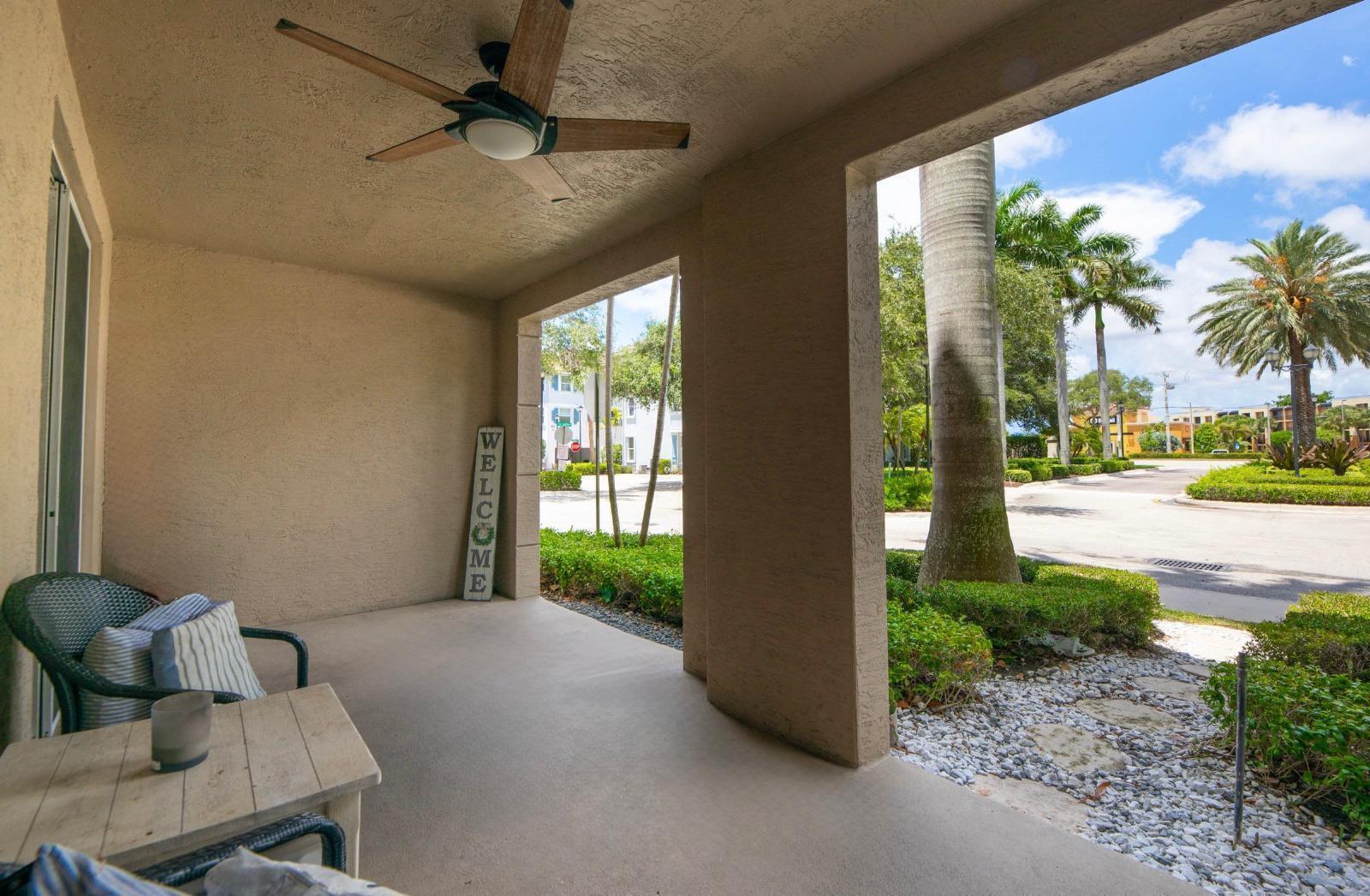 A covered patio features a ceiling fan, a small table with chairs, and a welcome sign — 3107 Renaissance Way, Boynton Beach FL 33426, BOYNTON BEACH, FL