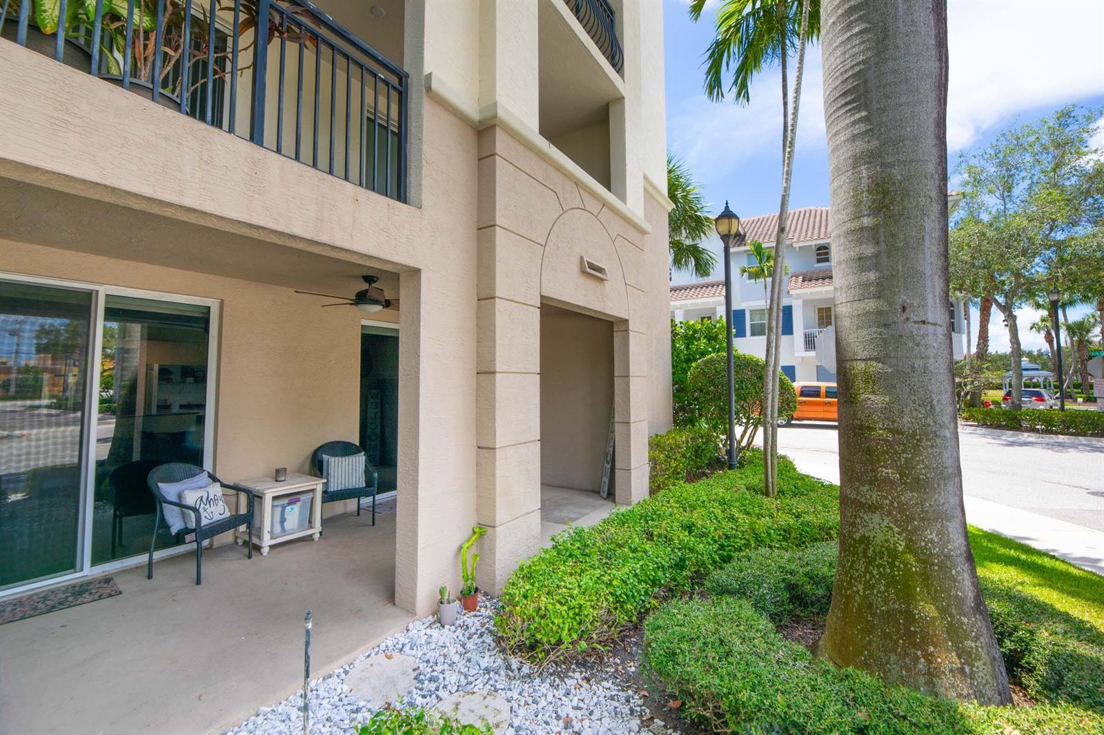 A ground-floor patio with two chairs and a small table sits beneath a building balcony — 3107 Renaissance Way, Boynton Beach FL 33426, BOYNTON BEACH, FL