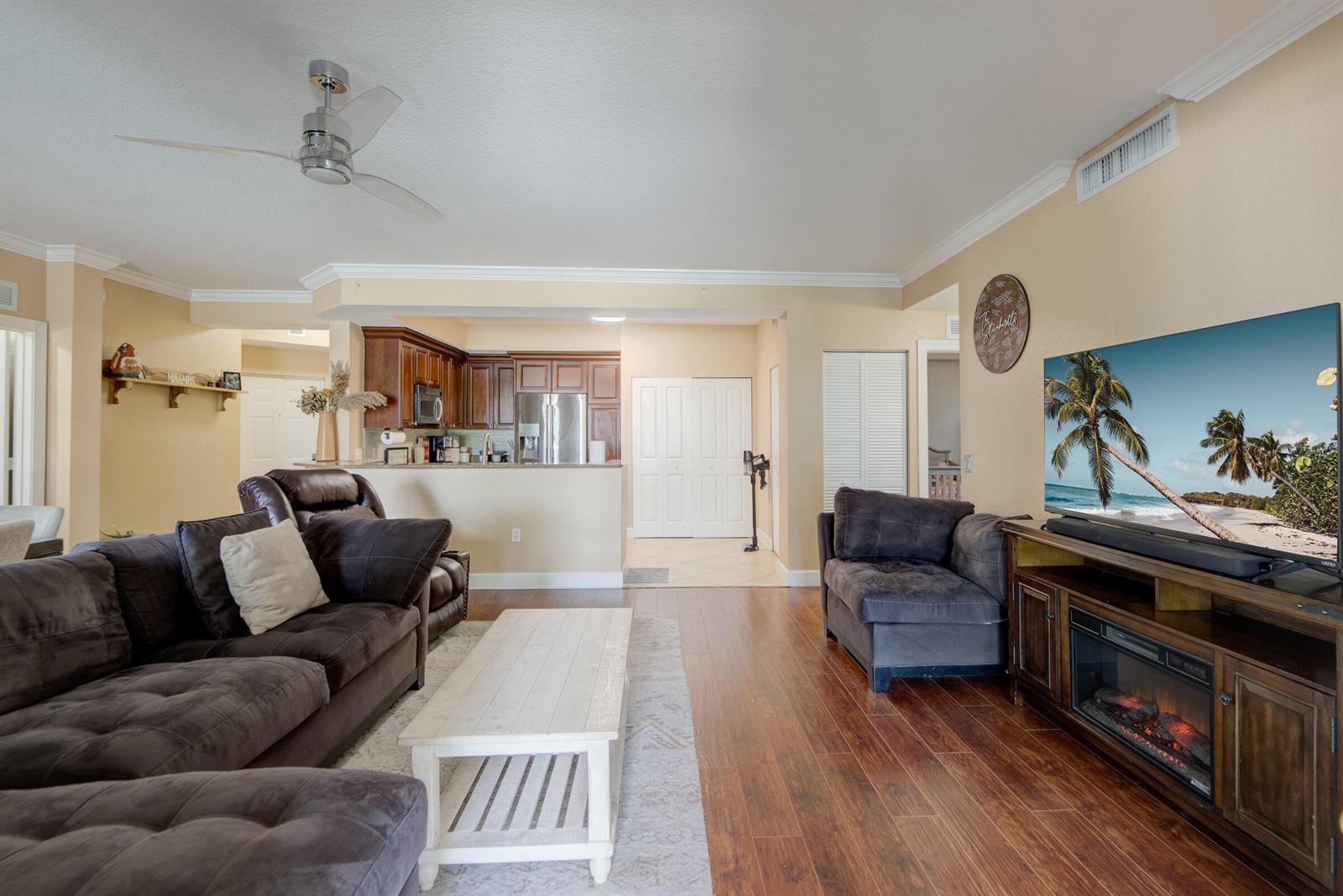 A living room with dark brown sofas, a white coffee table, and an open kitchen — 3107 Renaissance Way, Boynton Beach FL 33426, BOYNTON BEACH, FL