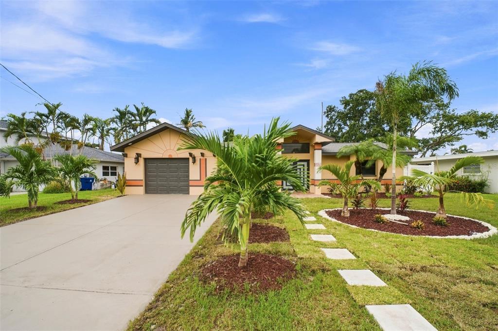 A single-story house with a garage, palm trees, and a concrete walkway in the front yard — 15918 REDINGTON DRIVE, REDINGTON BEACH, FL