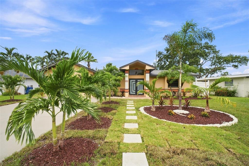 A single-story house with a tan exterior, a paved walkway, and several palm trees — 15918 REDINGTON DRIVE, REDINGTON BEACH, FL