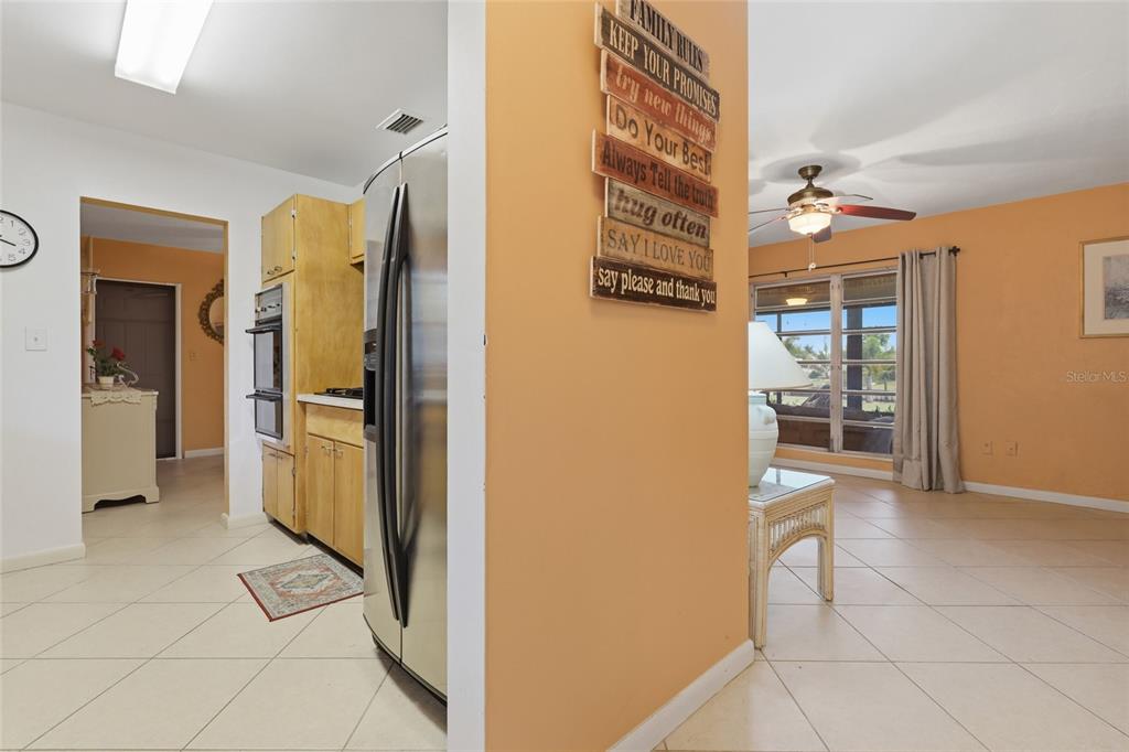 A kitchen with light wood cabinets and stainless steel appliances opens into a living area — 21444 HIGGS DRIVE, PORT CHARLOTTE, FL