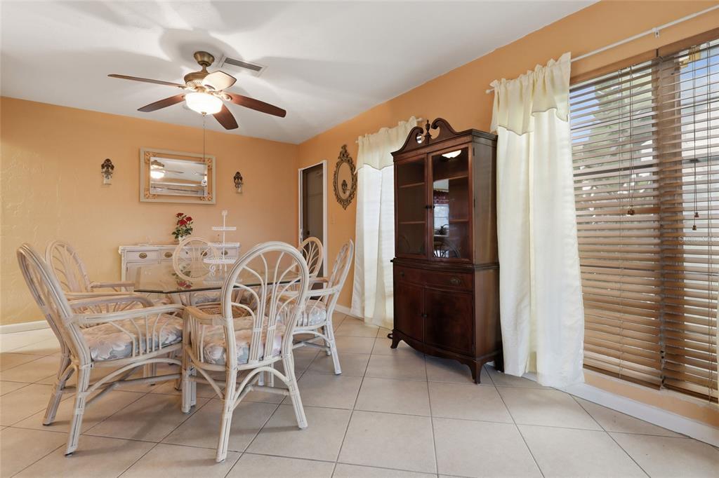 A dining room with a glass table, wicker chairs, tile floors, and a wooden hutch — 21444 HIGGS DRIVE, PORT CHARLOTTE, FL