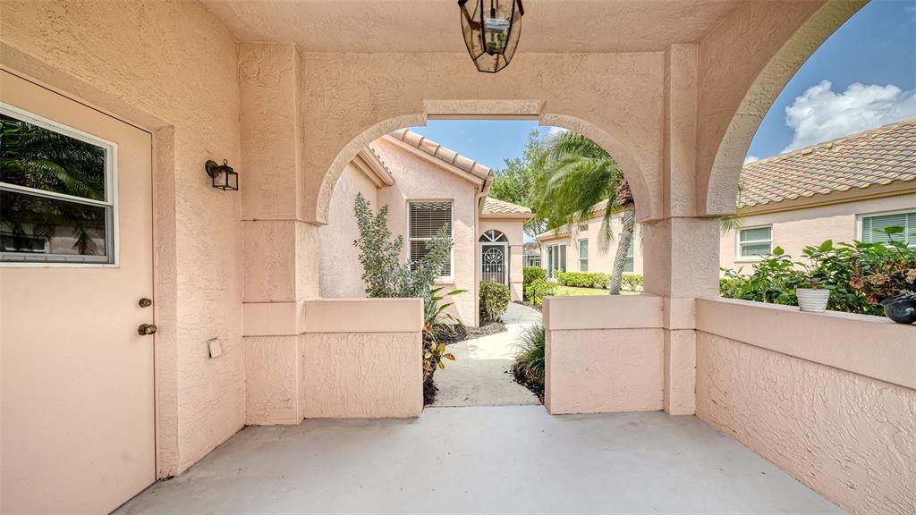 A covered outdoor patio with stucco walls, arched openings, and a concrete floor — 3799 MIRA LAGO DRIVE, SARASOTA, FL