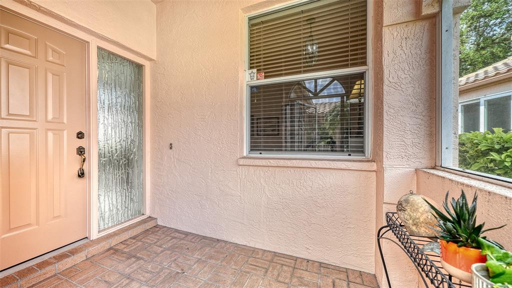 A covered entryway features a light-colored door, a window with blinds, and tiled flooring — 3799 MIRA LAGO DRIVE, SARASOTA, FL