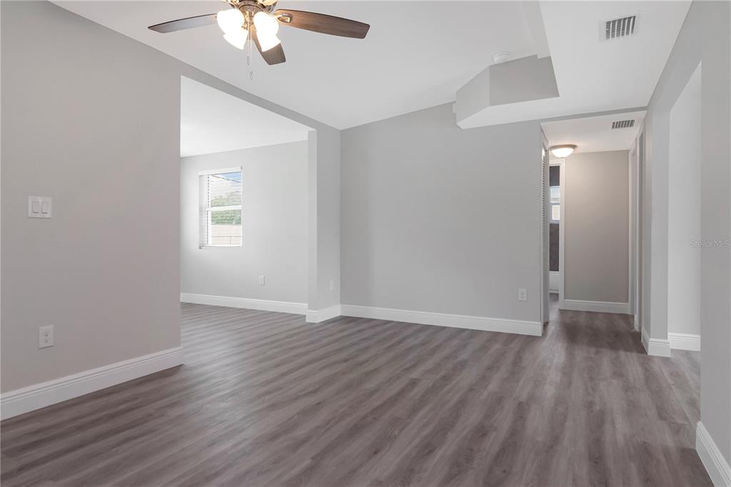An interior view of a room with gray walls, wood-look flooring, and a ceiling fan — 2216 E 109TH AVENUE, TAMPA, FL