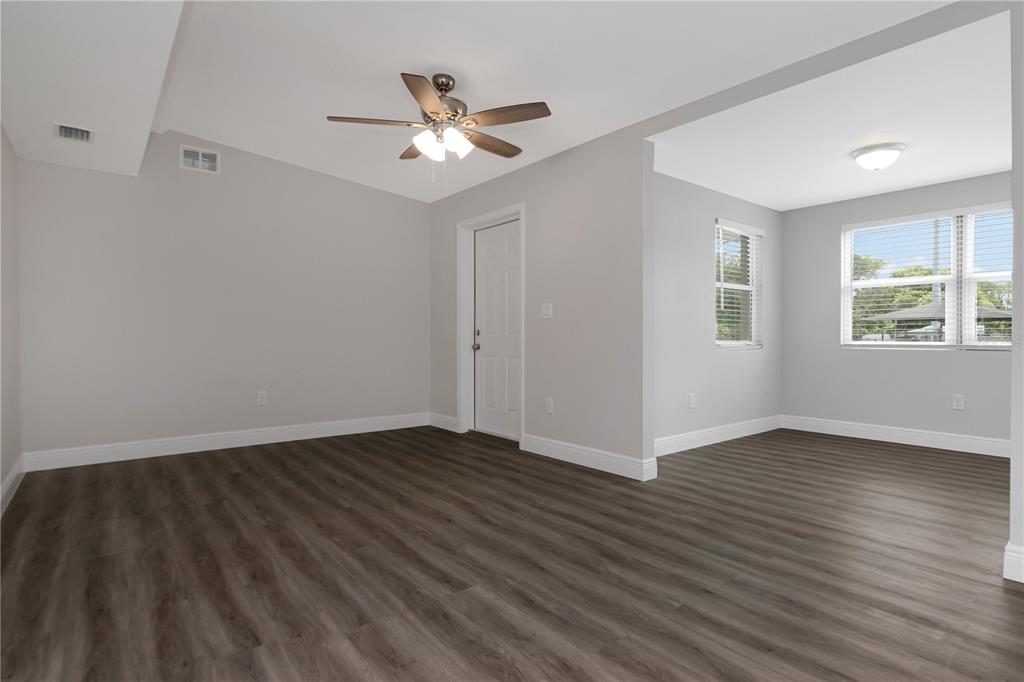 An empty room with gray walls, wood-look flooring, a ceiling fan, and two windows — 2216 E 109TH AVENUE, TAMPA, FL