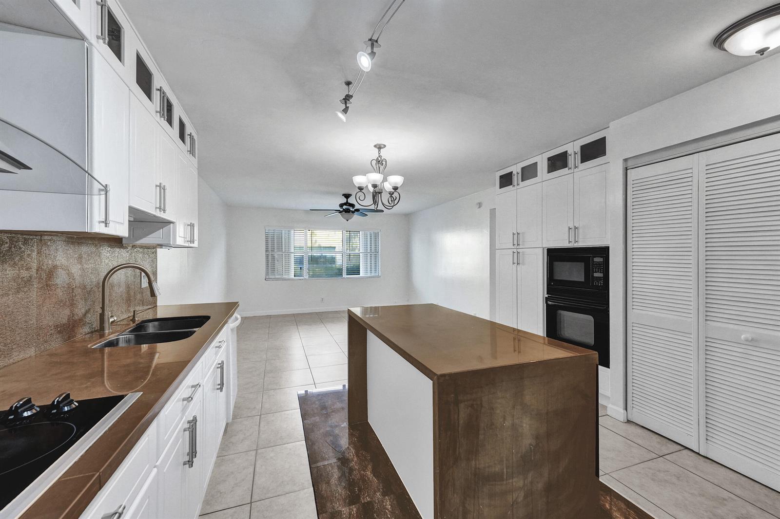 A kitchen features white cabinets, brown countertops, a central island, and tile flooring — 600 SE 2nd Avenue # K2, Deerfield Beach FL 33441, DEERFIELD BEACH, FL