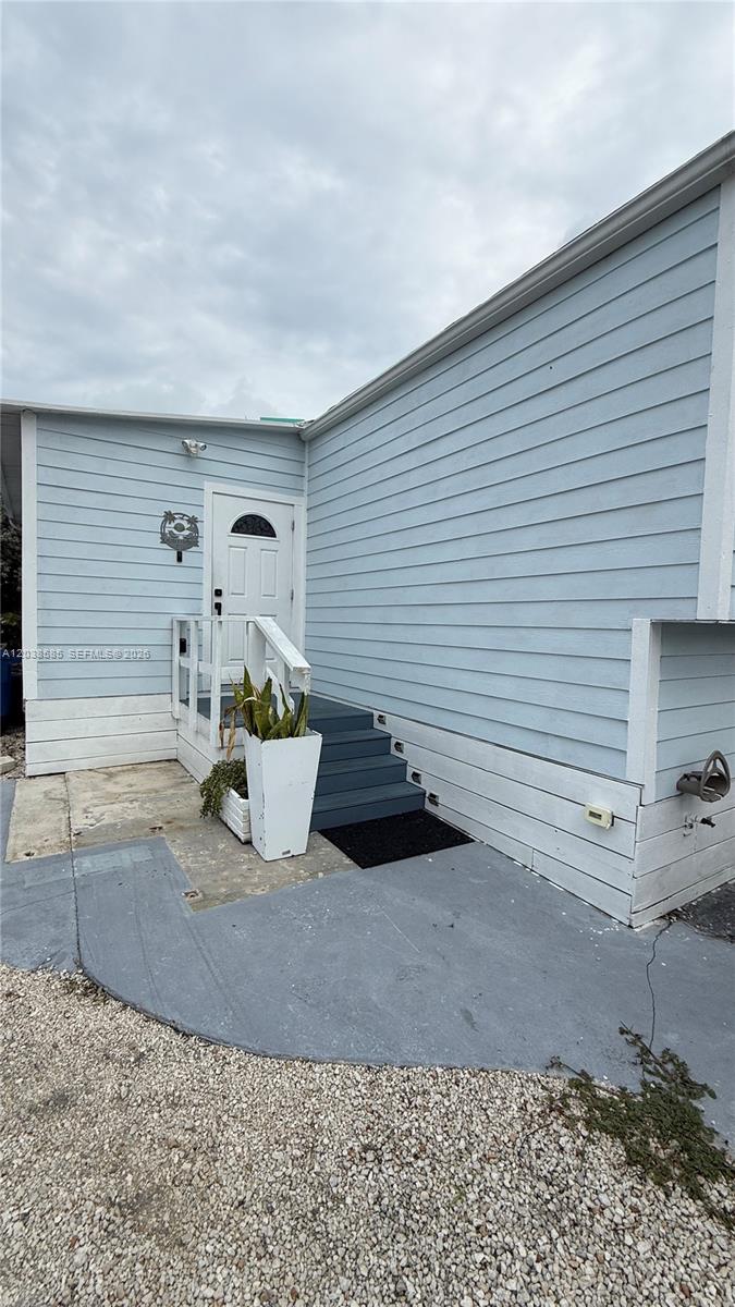 The exterior of a light blue house features a white door, stairs, and a planter — 65821 Overseas Hwy # 314, Long Key FL 33001, LONG KEY, FL