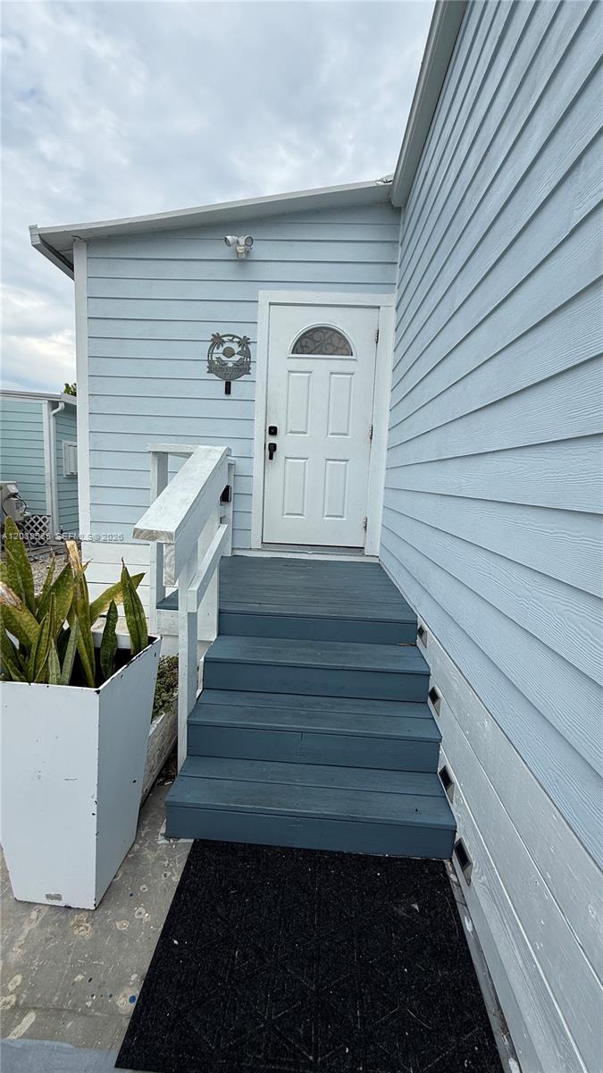 The exterior of a light blue house features a white front door and wooden steps — 65821 Overseas Hwy # 314, Long Key FL 33001, LONG KEY, FL