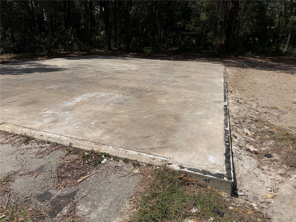 A rectangular concrete slab sits on a dirt lot bordered by trees — 1628 S PALM AVENUE, HOMOSASSA, FL